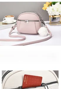 Detail of lychee pattern leather texture and multi-zipper structure on a mini crossbody bag
