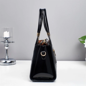 Side view of black faux crocodile leather handbag with glossy finish and gold metal D-rings
