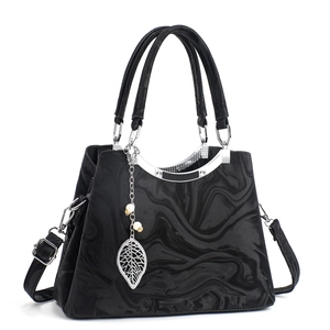 Détail du sac en cuir marbré noir avec pendentif feuille et garniture en métal argenté