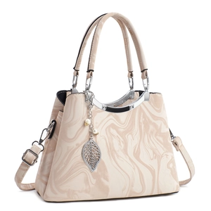 Détail du sac à main beige à motif marbre avec pendentif perle et finitions argent