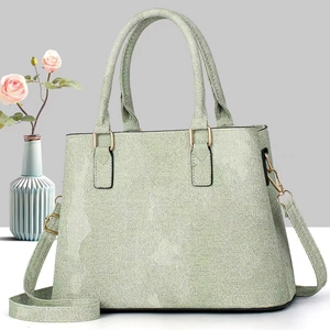 Detail of light green woven texture handbag with gold hardware and removable strap