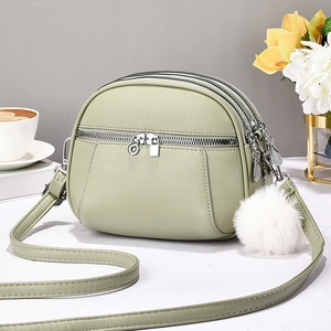 Light green pebble leather crossbody bag with triple zippers and plush ball charm