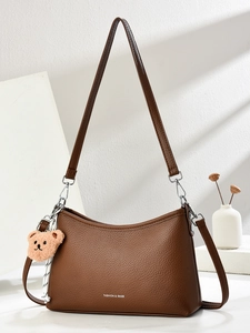 Brown litchi grain leather shoulder bag with plush bear pendant and dual straps
