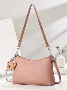 Detail of lychee pattern leather shoulder bag in dusty pink with plush bear charm