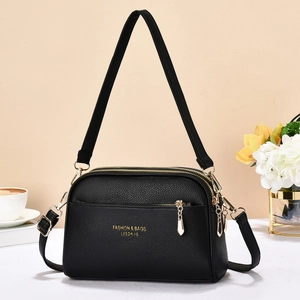 Macro shot of black lychee grain leather crossbody bag with premium gold zipper detail