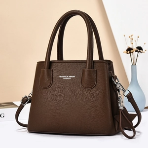 Brown litchi grain handbag with top handle and star charm on a minimal background