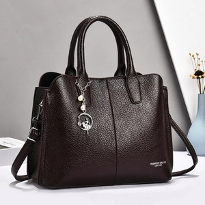 Detail of dark brown pebble leather handbag with pearl ballerina pendant and shoulder strap