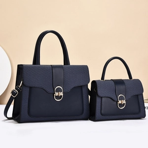 Detail of navy blue bag set featuring textured leather patchwork and golden metal lock