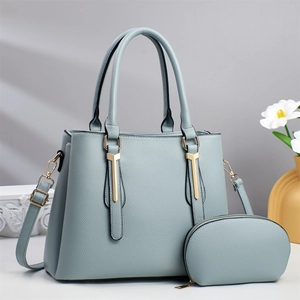 Detail of light blue textured leather tote bag with gold metal trim and small matching pouch