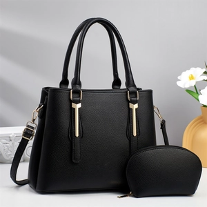 Detail of black pebbled leather handbag set with gold hardware and a matching pouch