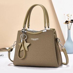 Olive green woven crossbody bag with leather handles and star charm on geometric background