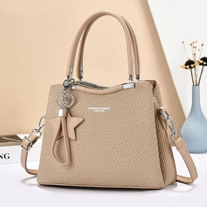 Elegant khaki woven crossbody bag with star tassel and dual handles on minimalist background