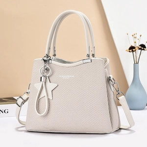 Detail of cream woven texture handbag with silver clasp and star charm on soft studio background