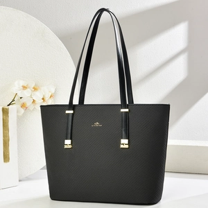 Classic black woven tote bag with gold hardware and shoulder straps in a modern studio setting