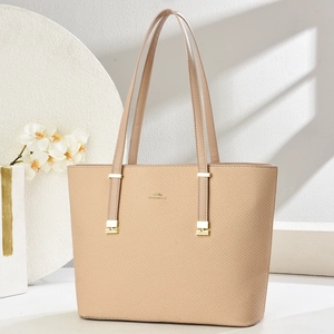 Close-up of beige tote bag showing twill texture, gold logo, and premium metal hardware