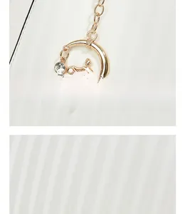 Detail of golden moon and ballet dancer pendant with sparkling rhinestone on white leather