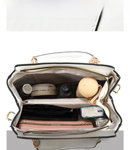 Detail of white tote bag internal storage and reinforced gold hardware handles