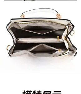 Detailed interior of the white handbag showing multi-layer compartments and grey lining
