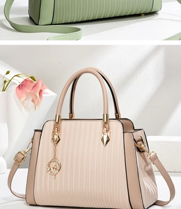 Detail of elegant pleated tote bag with golden hardware and ballet dancer charm
