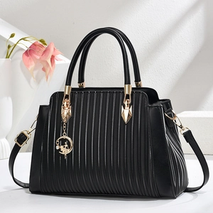 Elegant black pleated tote bag with golden ballerina charm and adjustable strap