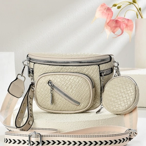 Detail of cream textured crescent bag with small round coin purse and stud canvas strap