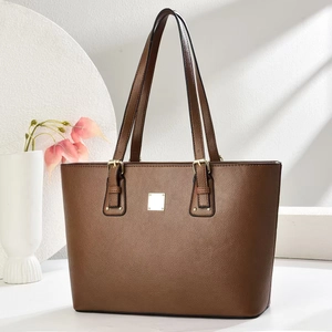 Minimalist brown lychee leather tote bag with gold buckle on geometric background