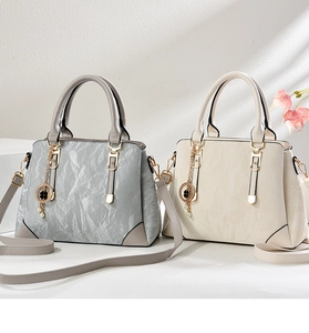 Detail of elegant pleated texture tote bags with clover pendants in blue and beige colors