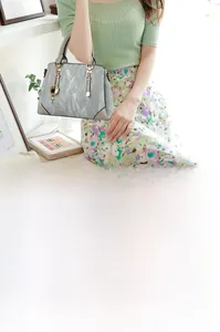 Detail of grey pleated texture handbag with gold clover charm and retro trapezoid design