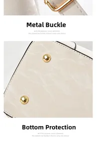Detail of light beige leather handbag with gold hardware and protective metal bottom studs