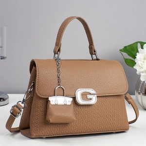 Detail of a brown leather bag with a crystal G buckle and woven texture finish
