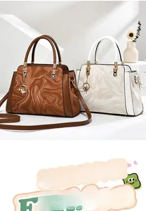 Detail view of large commuter handbag with marble print, gold hardware, and round charm