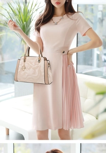 Detail of a beige marble pattern handbag paired with a pale pink pleated dress