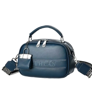 Deep blue lychee leather crossbody bag with geometric strap and mini charm accessory