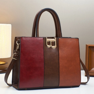 Detail of a color-block leather handbag with vintage B-shaped metal buckle and stitchings