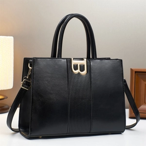 Black large capacity tote bag with gold B buckle and adjustable strap in a cozy setting