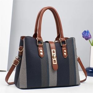 Detail of blue striped fabric handbag with brown leather handles and gold metal hardware