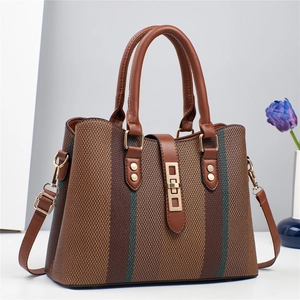Detail of vintage striped woven fabric texture and premium brown leather handles on handbag