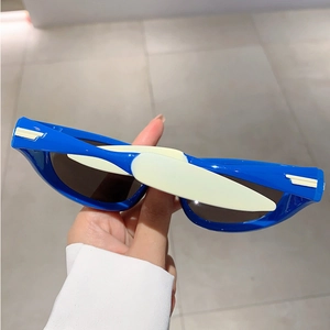 Close-up of blue Y2K cat-eye sunglasses with contrast color hinges and metal accents