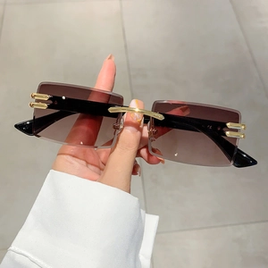 Close-up of rimless square sunglasses with brown gradient lenses and gold metal accents