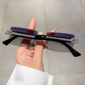 Detailed close-up of rimless rectangular sunglasses with silver metal hinge accents