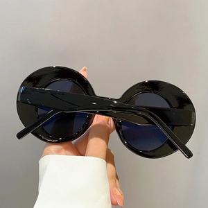 Detail of retro black oversized round sunglasses with glossy frames and dark lenses