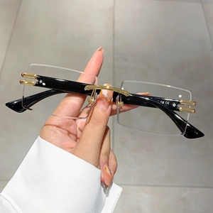 Detail of rimless rectangular sunglasses with gold metal bridge and sleek black temples