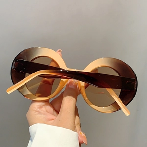 Detail of round frame sunglasses with brown gradient frames and thick retro temples