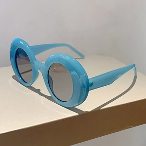 Detail view of stylish round blue thick frame sunglasses with grey lenses on display stand