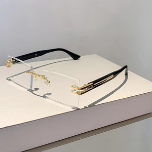 Close-up of rimless rectangular sunglasses with gold bridge and black temple accents