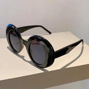 Macro detail of glossy black thick-frame round sunglasses with grey lenses
