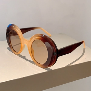 Close-up of retro thick round tortoiseshell frames and brown lenses on a gray stand