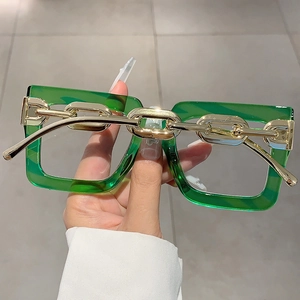 Detail of square green frames with gold-colored chain temple design on stylish glasses