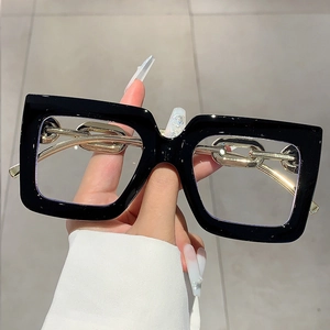 Close-up of black square frame glasses with chunky gold metal chain temple design