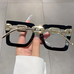 Detail of square oversized glasses frame with bold golden chain accent on black temples
